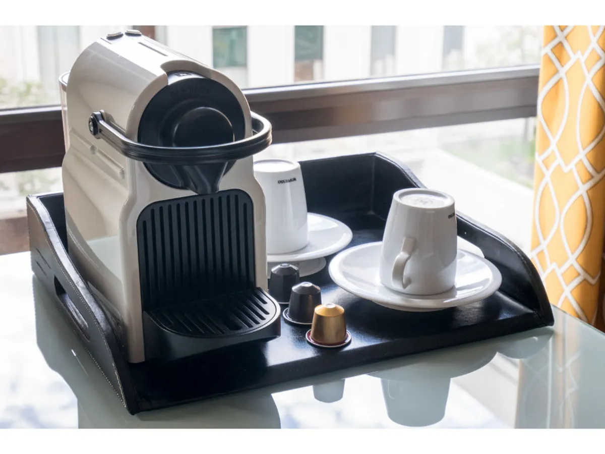 A close-up view of a coffee machine with coffee cups, sugar cubes, and coffee capsules arranged invitingly. The scene radiates morning ritual energy and personal comfort.