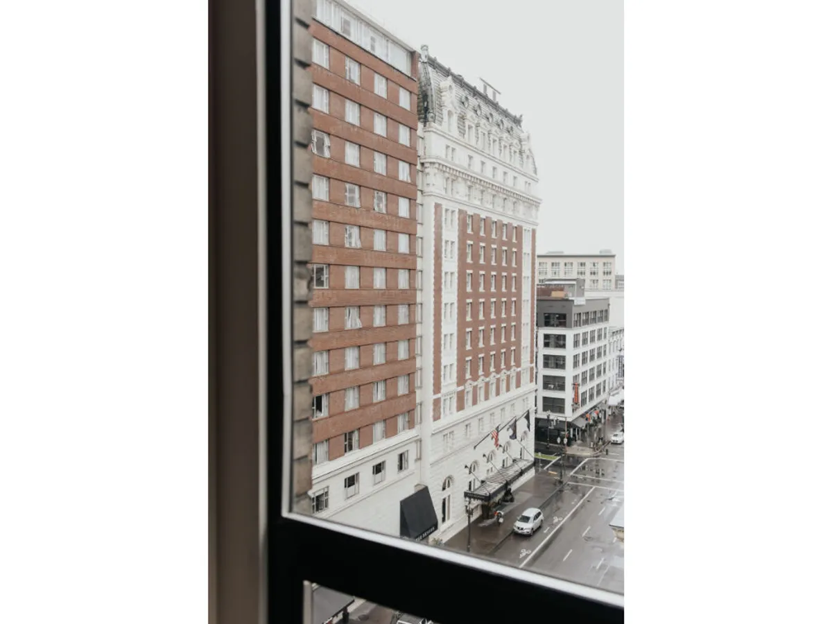A rain-soaked city street lined with historic buildings, filled with people enjoying cafes and local shops. The atmosphere is both nostalgic and energetic, highlighting daily urban life and the unique charm of Portland’s architecture.