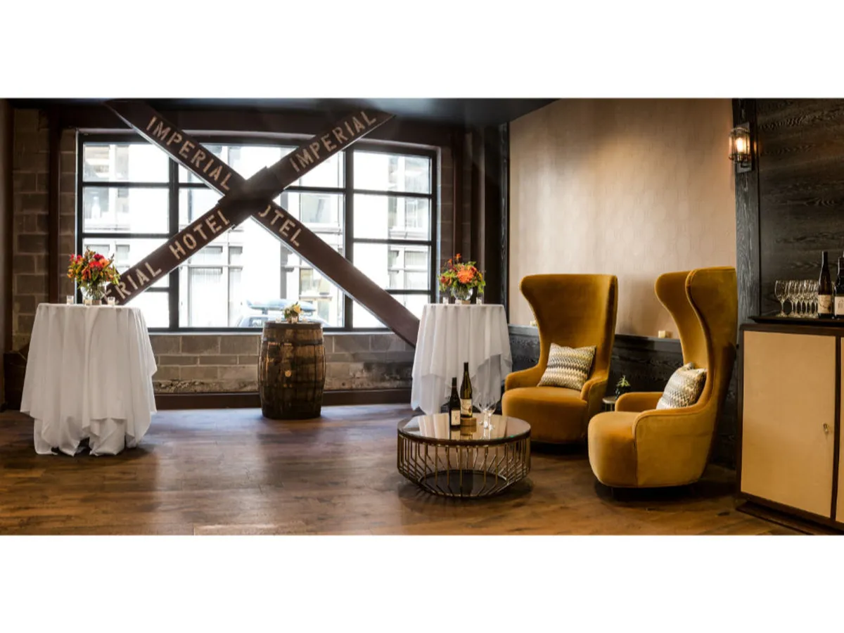 An elegant setting with high-back yellow chairs, round tables dressed in crisp white tablecloths, fresh floral arrangements, and glassware—ideal for celebrations, conversations, and shared laughter among small groups.