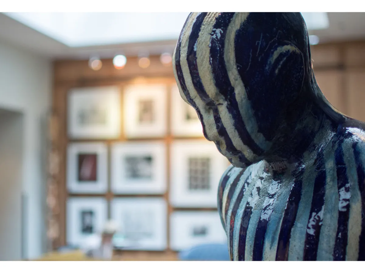 A thoughtfully curated gallery wall adorned with framed artwork serves as the backdrop, complemented by a striking striped sculpture. The arrangement suggests an open, inviting common area that fosters social interaction and art appreciation.